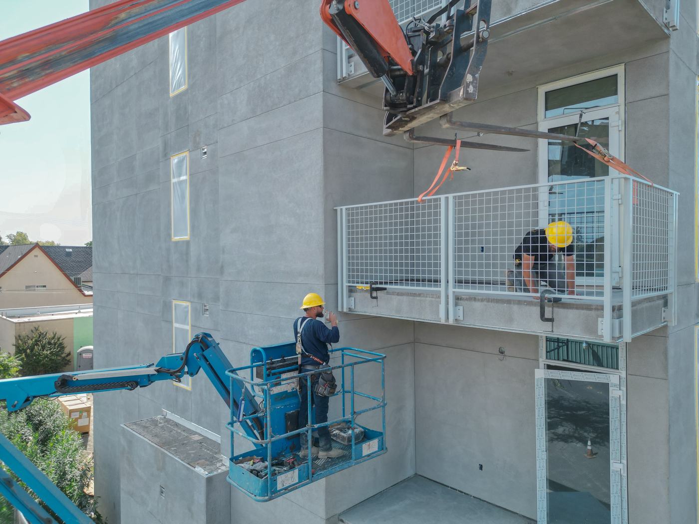 Crew installing balcony railings from aerial lifts
